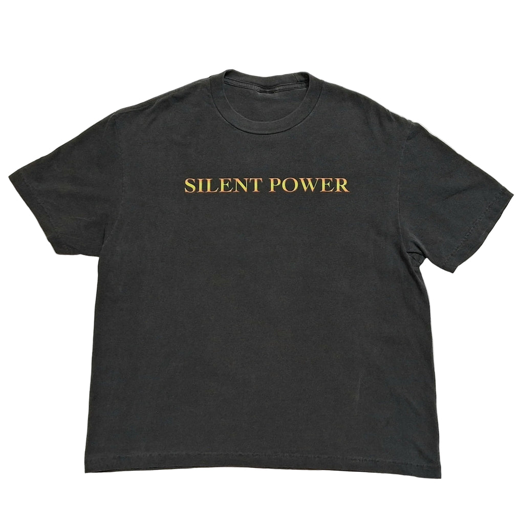 A dark charcoal gray short-sleeve t-shirt with the words 'SILENT POWER' printed in gold serif lettering across the chest, laid flat against a light gray background.